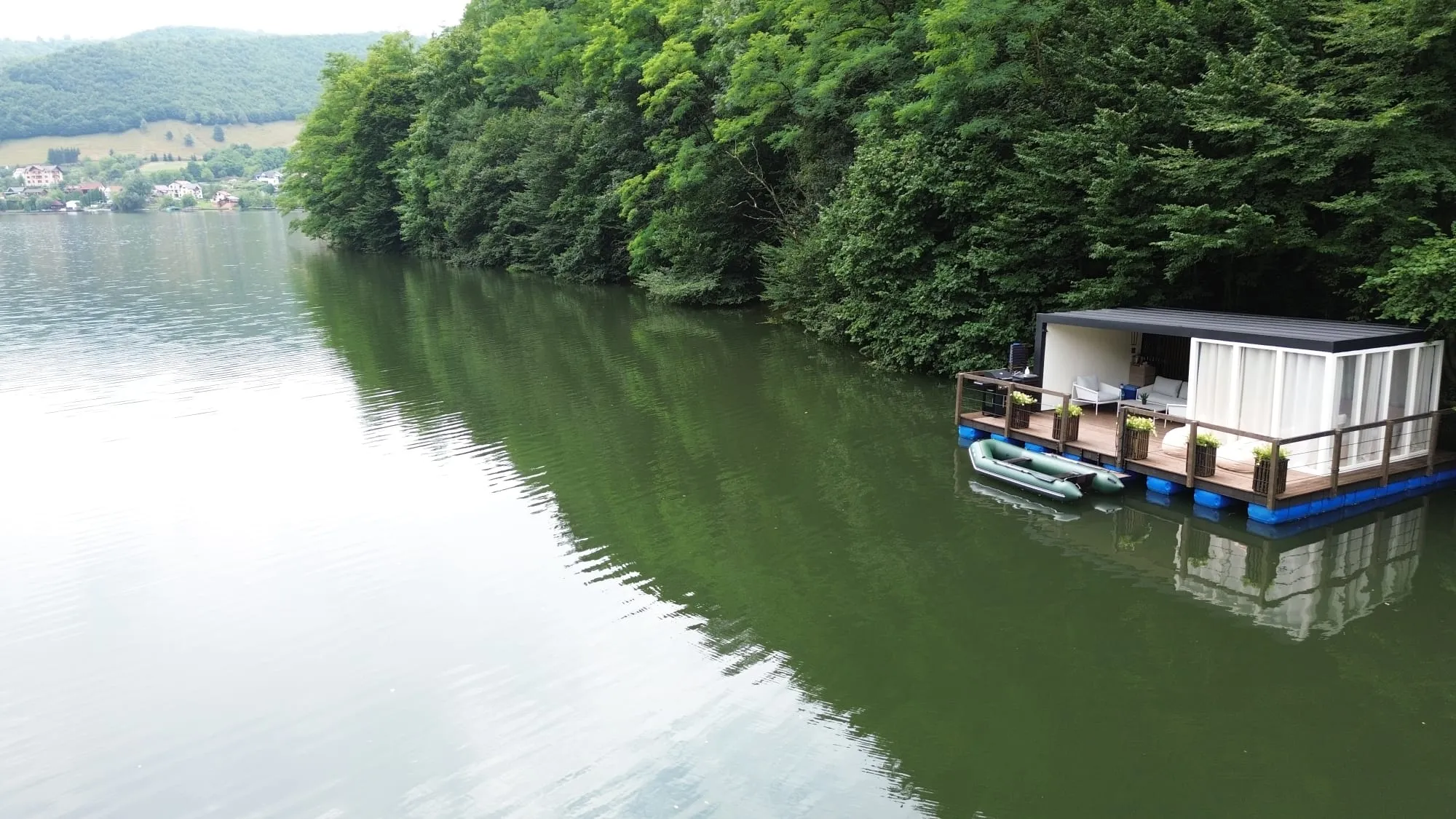 Casa plutitoare pe lacul Someșul Cald, văzută de pe apă, cu pădurea în jur